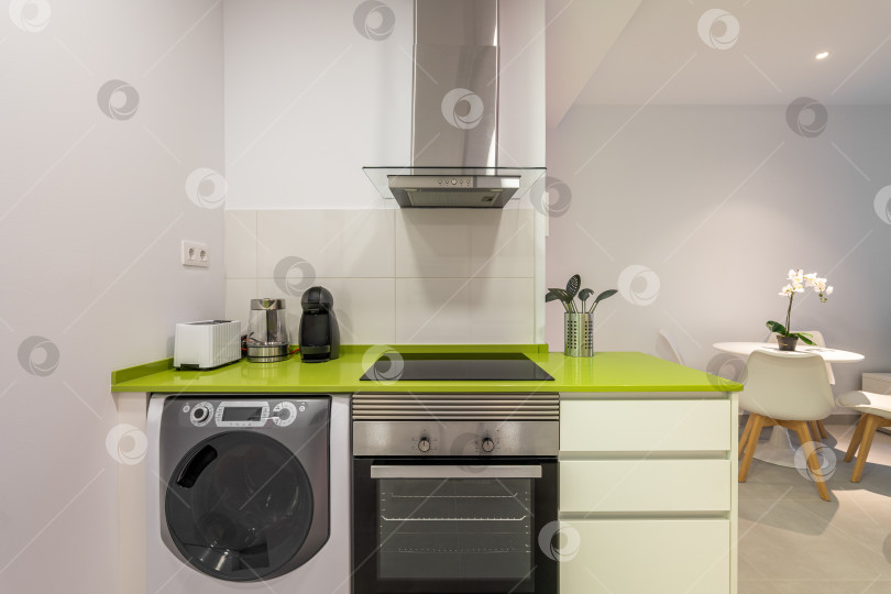 Скачать Уютная светлая стильная кухня в зелено-белых тонах с высокотехнологичной бытовой техникой и стильной мебелью. Концептуальная кухня в новом здании после ремонта фотосток Ozero