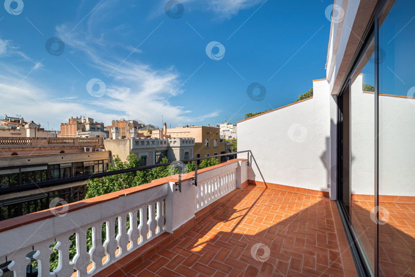 Скачать Пустая солнечная терраса, балкон отремонтированной квартиры с видом на улицу и голубое небо в центре Барселоны фотосток Ozero