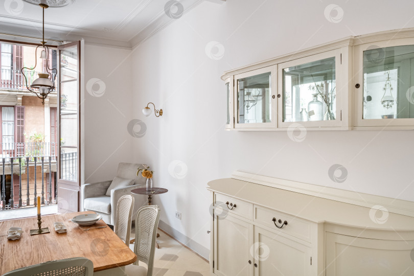 Скачать Легкий сервант в классической гостиной в стиле ретро с деревянным обеденным столом на двоих. фотосток Ozero