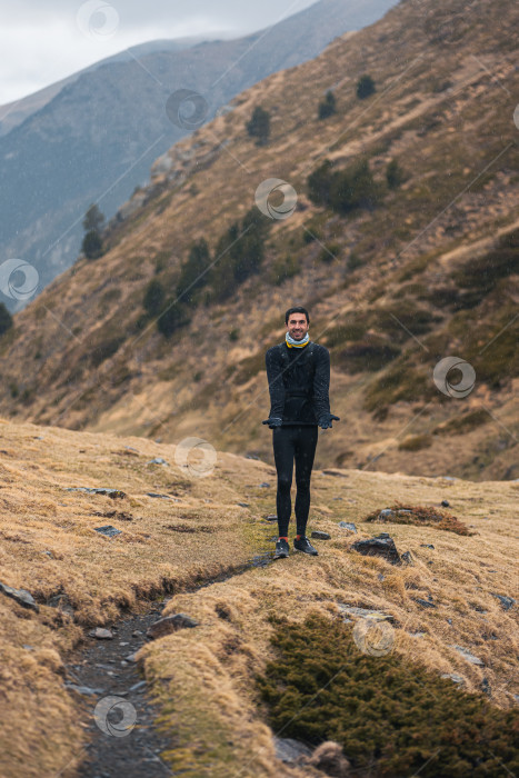 Скачать Человек стоит на тропинке в горах и радуется дождю после длительного периода засухи в Испании. фотосток Ozero