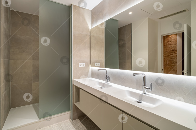 Скачать Современная ванная комната, отделанная кафелем, с душевой кабиной, двумя раковинами и большим настенным зеркалом фотосток Ozero