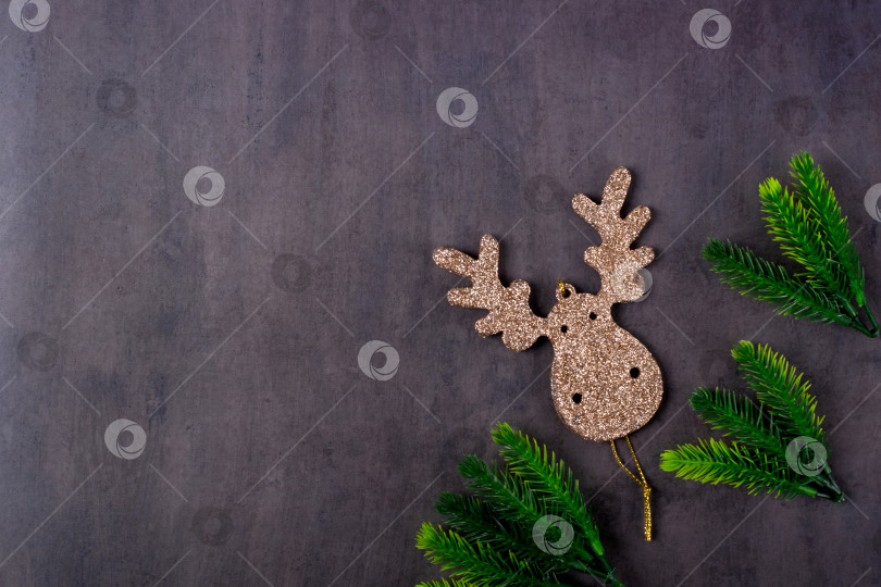 Скачать Рождественский фон с украшением в форме золотого оленя на сером столе. фотосток Ozero