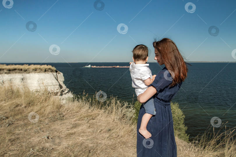 Скачать Мать и сын смотрят на корабли стоя на вершине утёса. фотосток Ozero