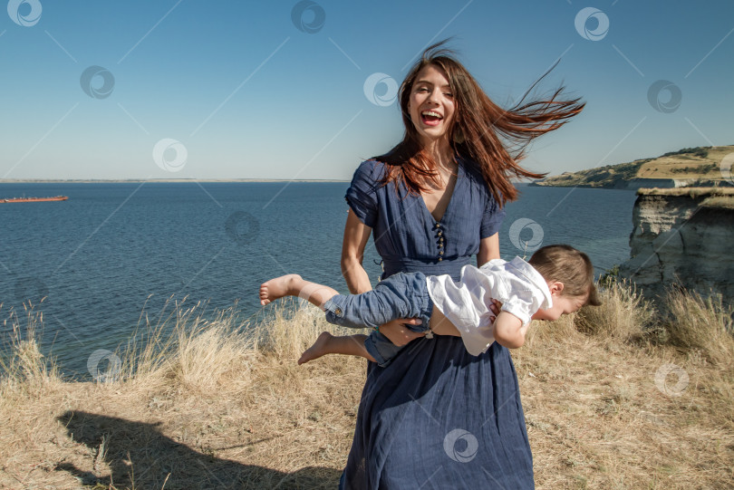 Скачать Молодая женщина держит в руках смеющегося ребёнка. фотосток Ozero
