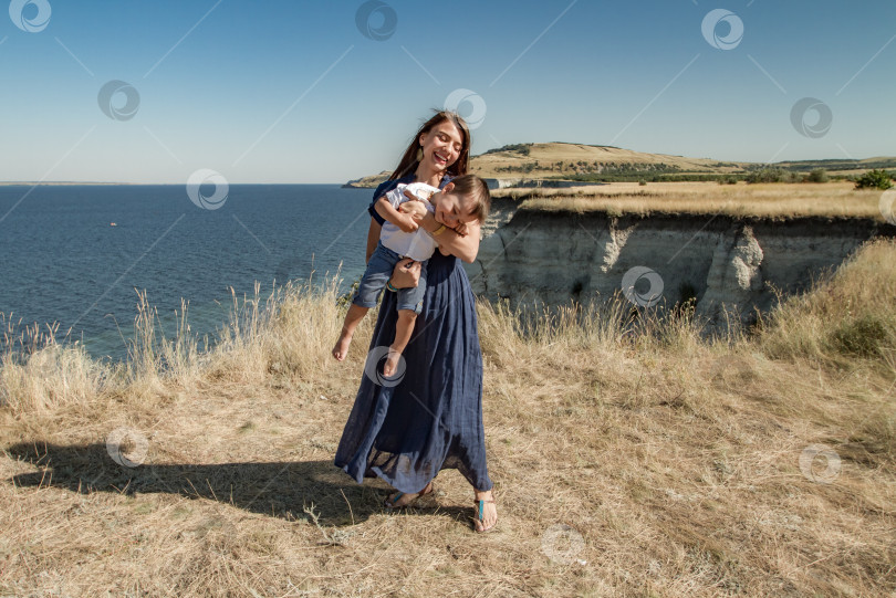 Скачать Молодая женщина держит в руках смеющегося ребёнка. фотосток Ozero