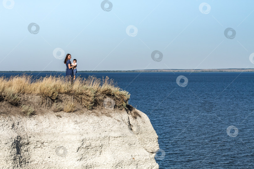 Скачать Женщина с ребёнком на руках стоит на краю утёса. фотосток Ozero