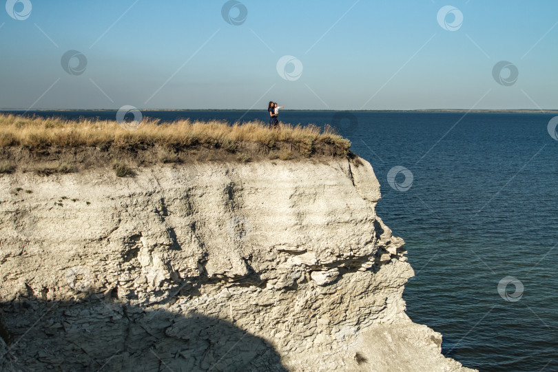 Скачать Мать и сын смотрят на корабли стоя на вершине утёса. фотосток Ozero