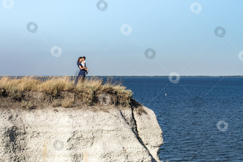 Скачать Мать и сын смотрят на корабли стоя на вершине утёса. фотосток Ozero