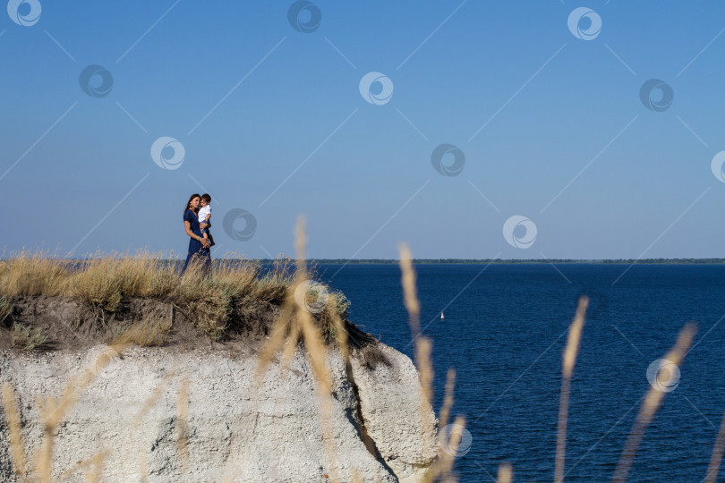 Скачать Мать и сын смотрят на корабли стоя на вершине утёса. фотосток Ozero