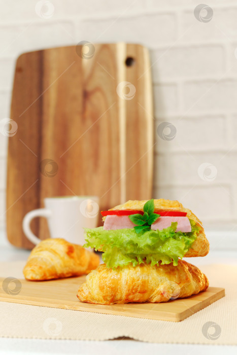 Скачать Бутерброды с круассанами с ветчиной, листьями салата и сыром. Крупный план. Выборочный фокус, завтрак. Вертикальное фото фотосток Ozero