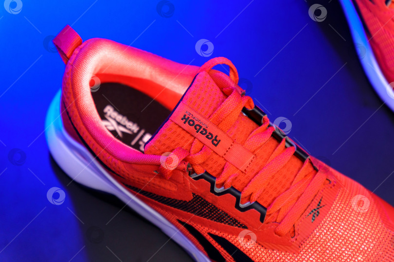 Скачать Тюмень, Россия-03 августа 2023 года: Стильная спортивная обувь Reebok красного цвета. Разноцветный свет. Избирательный подход фотосток Ozero