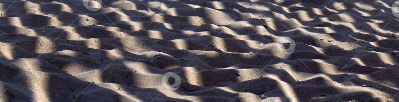 Скачать Морской песок создает волнистую поверхность. Волнистые тени падают на освещенный песок под углом, создавая интересный узор. Абстрактный естественный фон для дизайна. фотосток Ozero