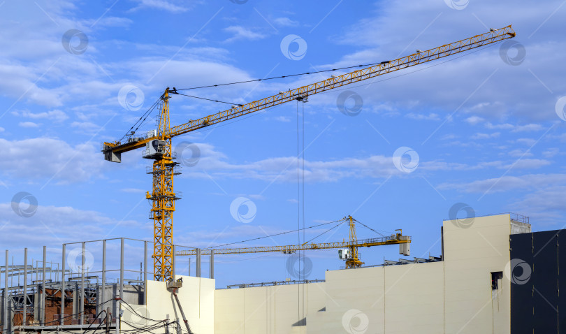Скачать Два башенных крана работают на строительстве большого здания. Промышленный фон со строящимся зданием и башенными кранами. Панорама. фотосток Ozero