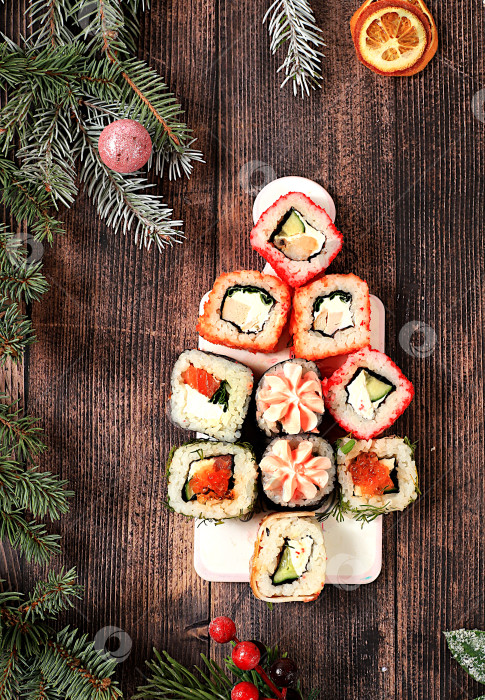 Скачать Рождественская елка из свежих суши-роллов с соусом на деревянном фоне, Рождественская новогодняя еда, баннер для рекламы магазина, бара, меню для кафе, традиционная японская кухня, место для текста, фотосток Ozero