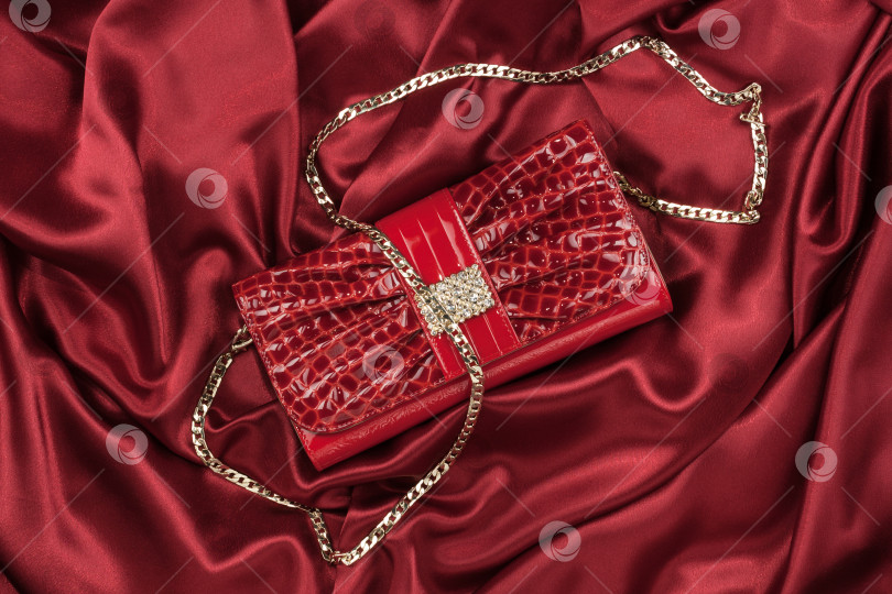 Скачать Красная лаковая сумка, лежащая на красном шелке в качестве фона. Красная лаковая сумка, лежащая на красном шелке в качестве фона фотосток Ozero