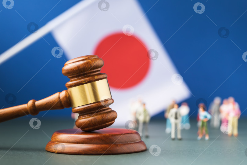 Скачать Судейский молоток, японский флаг и пластмассовые игрушечные человечки на цветном фоне - концепция судебного разбирательства в японском обществе фотосток Ozero