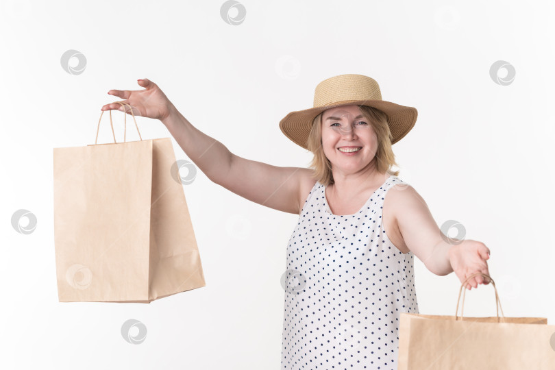 Скачать Женщина-покупатель в белом платье держит в руках пакеты для покупок из крафт-бумаги на белом фоне фотосток Ozero