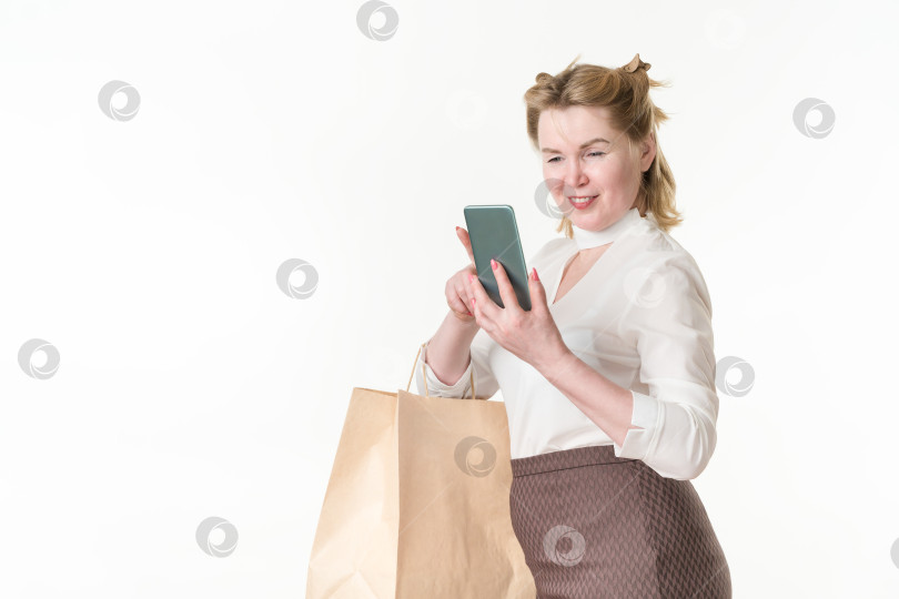 Скачать Жизнерадостная женщина со смартфоном в руках читает онлайн-сообщения, просматривает предложения с распродажами и скидками фотосток Ozero
