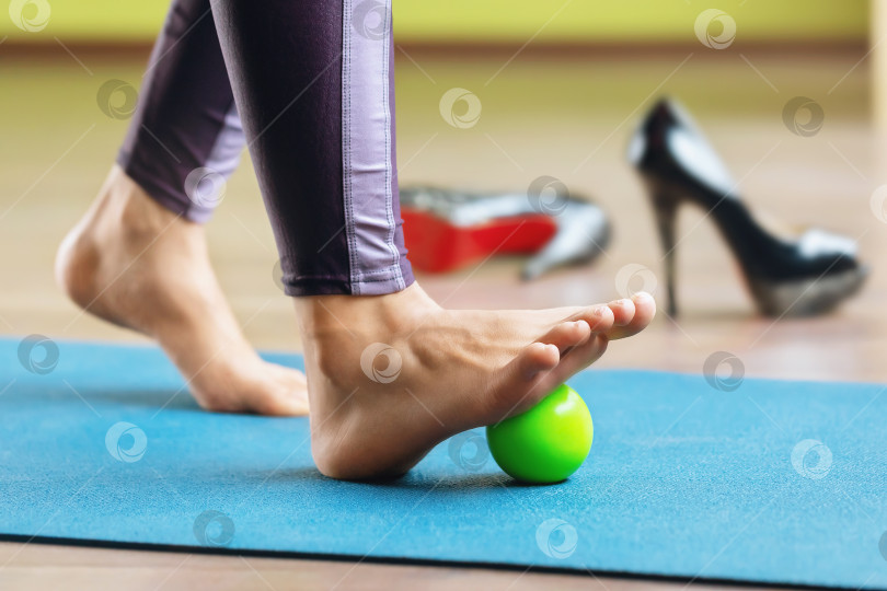 Скачать Миофасциальное расслабление гипермобильных мышц стопы с помощью массажного шарика, стоящего на коврике в студии. Профилактика усталости ног после ношения обуви на высоком каблуке фотосток Ozero