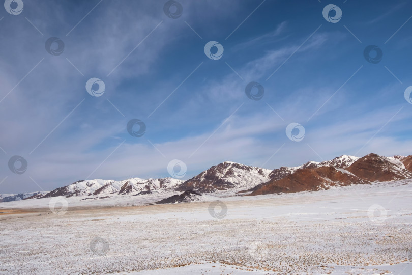 Скачать Снежная гора в Монголии. Живописный пейзаж со снежной вершиной горы. Прекрасный вид с каменистой снежной горы на горный хребет под голубым небом в солнечный день. фотосток Ozero