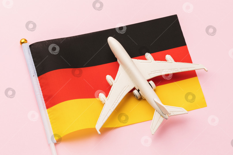 Скачать Флаг Германии и игрушечный самолет на розовом фоне, концепт на тему путешествия по стране фотосток Ozero