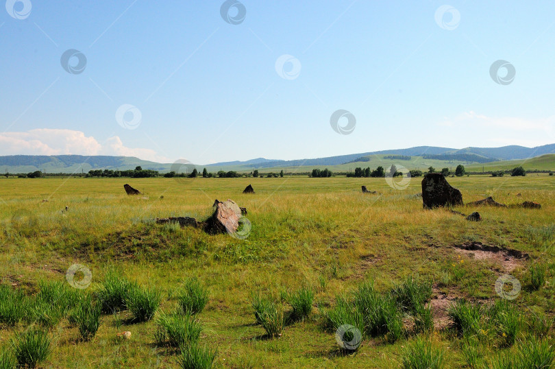 Скачать Разграбленное древнее захоронение с большими камнями в холмистой степи под летним пасмурным небом. фотосток Ozero