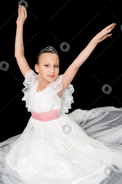 Скачать Девушка-балерина в белом длинном платье сидит на черном фоне и элегантно позирует с поднятыми руками фотосток Ozero