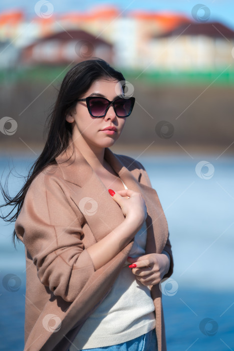 Скачать Портрет стильной молодой женщины с длинными волосами, пухлыми губами и солнечными очками, одетой в бежевое пальто фотосток Ozero
