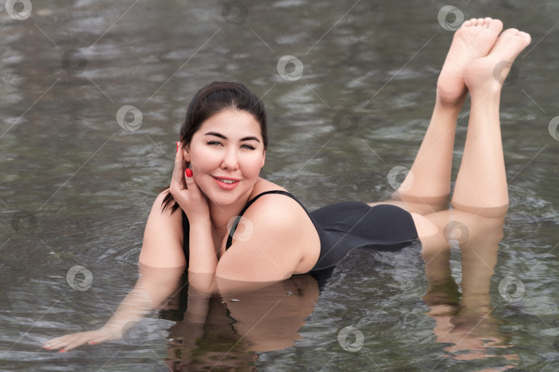 Скачать Молодая женщина в черном цельном купальнике лежит в открытом бассейне спа-центра hot springs resorts фотосток Ozero