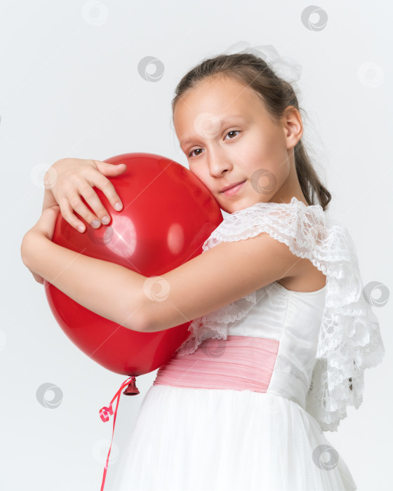 Скачать Портрет романтичной девушки, обнимающей красный воздушный шар и загадочно смотрящей вдаль на белом фоне фотосток Ozero