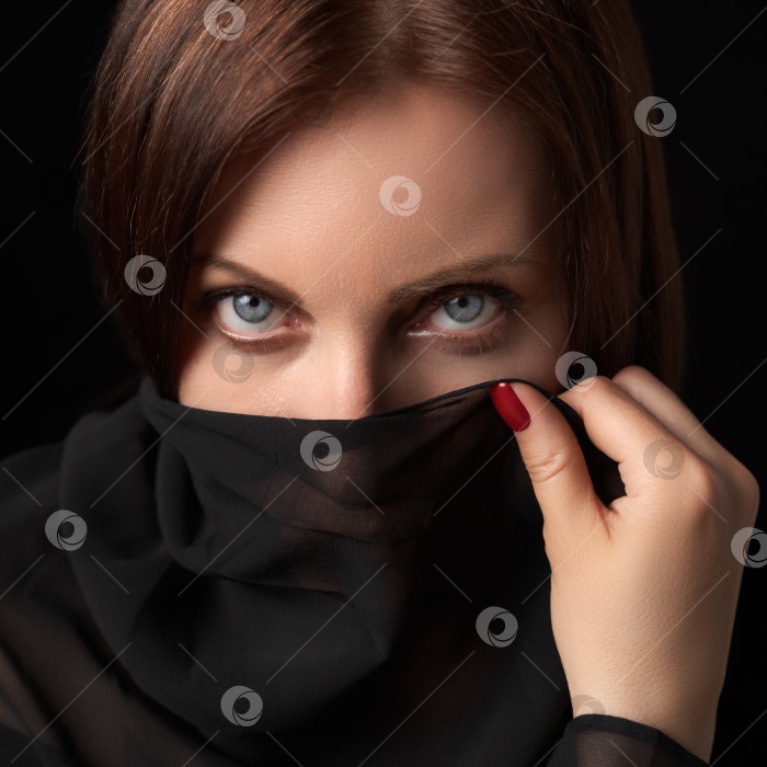 Скачать Портрет застенчивой женщины, прикрывающей рот и нос или лицо шарфом и смотрящей в камеру фотосток Ozero