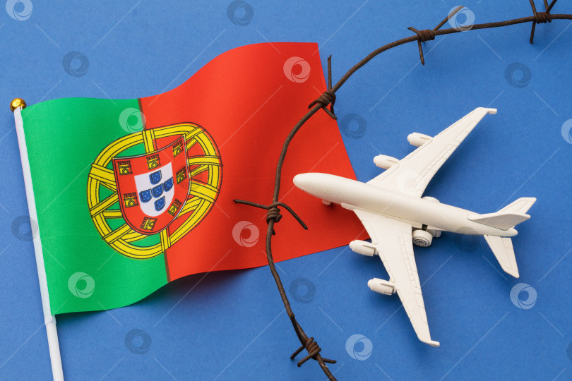 Скачать Игрушечный самолет, португальский флаг и колючая проволока на цветном фоне, концепция нарушения воздушной границы Португалии фотосток Ozero