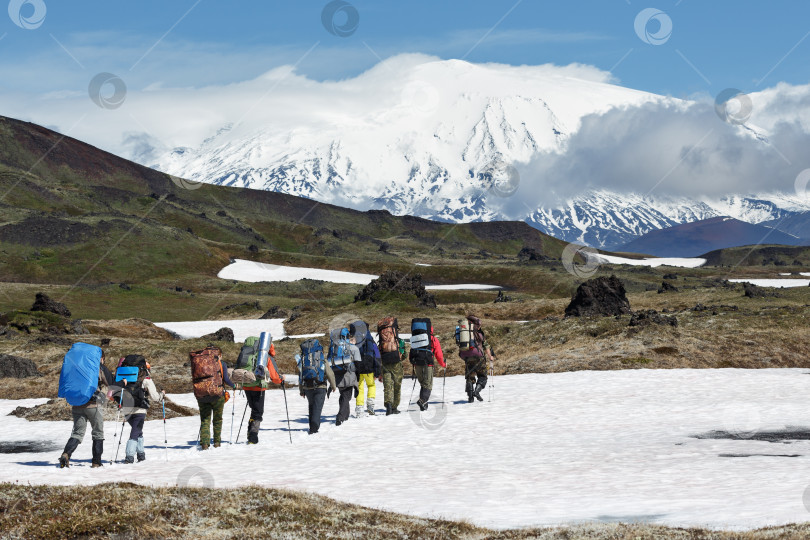 Скачать Группа туристов поднимается в гору на фоне вулканов фотосток Ozero