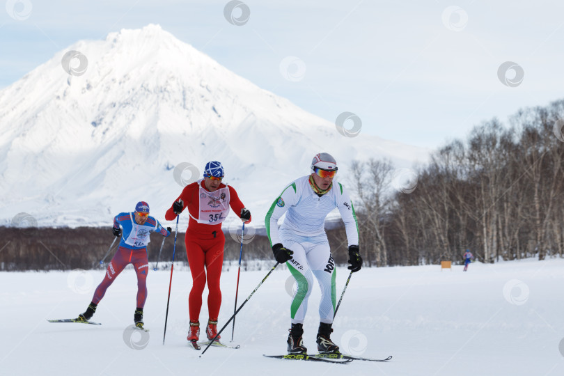 Скачать Лыжники-мужчины бегут по зимней лыжне на фоне Корякского вулкана фотосток Ozero