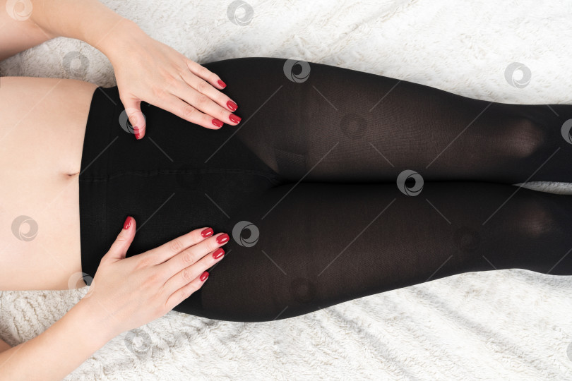 Скачать Укороченный вид женского тела сверху от талии до чуть ниже колен в черных компрессионных обтягивающих колготках фотосток Ozero