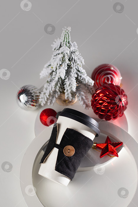 Скачать Белый керамический стакан для горячего напитка. Кофейная кружка с новогодними шарами и рождественской елкой на обратной стороне. Рождественская акция, реклама. Кофе в дорогу, доставка фотосток Ozero