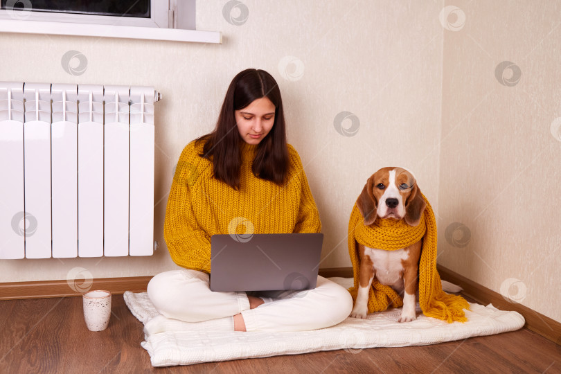 Скачать Девушка в теплой одежде сидит на полу в доме со своей собакой. фотосток Ozero