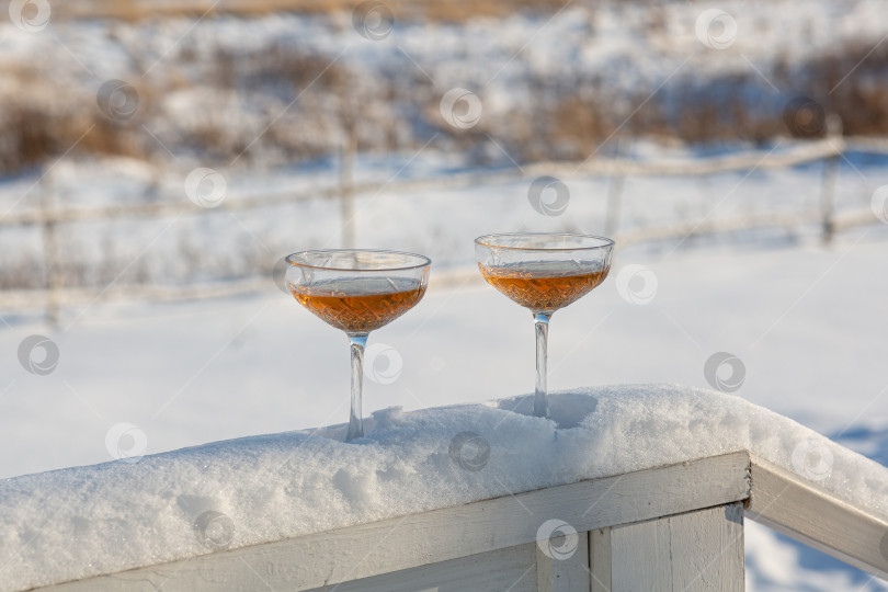 Скачать Два бокала шампанского на заснеженных перилах дома фотосток Ozero