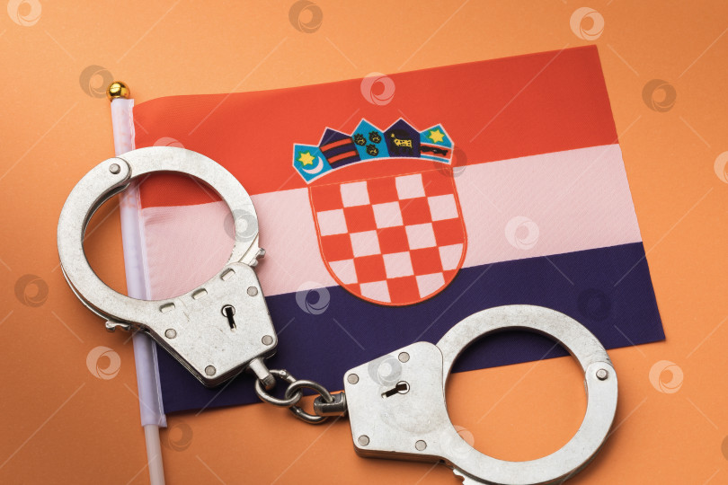 Скачать Флаг Хорватии и наручники на оранжевом фоне, концепция преступности в хорватском обществе фотосток Ozero