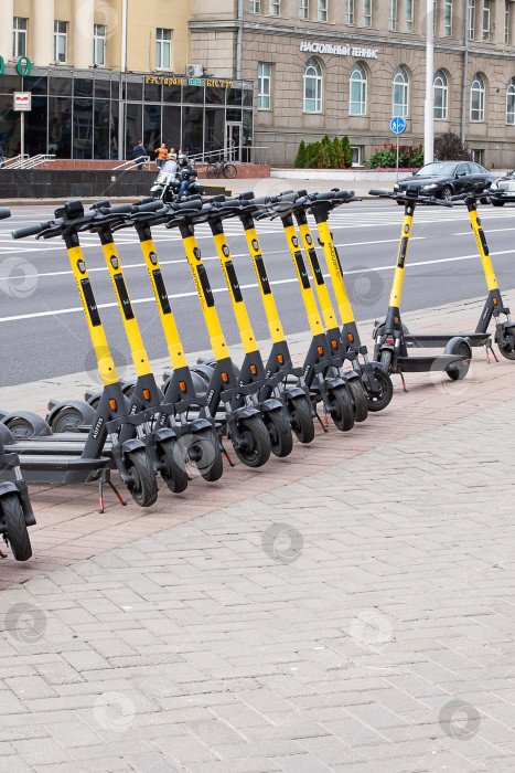 Скачать Беларусь, Минск - 03 сентября 2022 года: Электрические скутеры в ряд на тротуаре фотосток Ozero