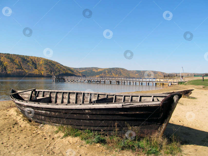 Скачать старая деревянная лодка на песчаном берегу, мост через реку, горы, покрытые лесами, осенний день фотосток Ozero