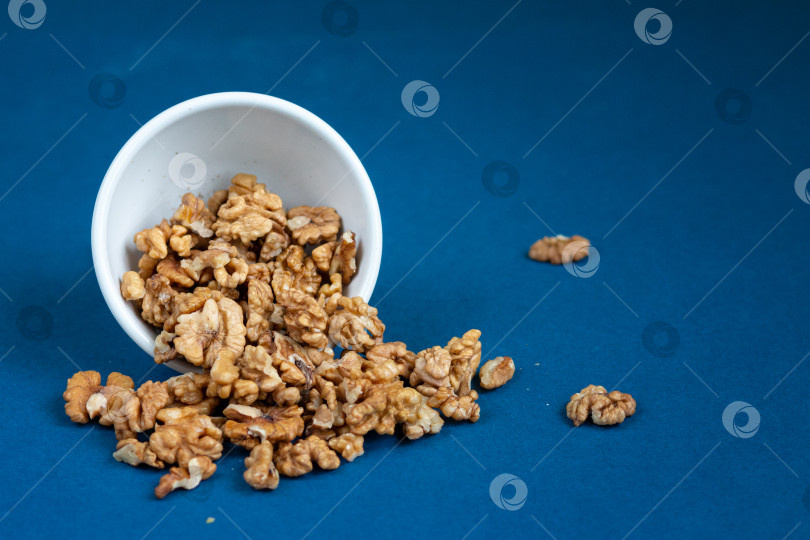 Скачать Группа грецких орехов в белой миске на синем фоне фотосток Ozero