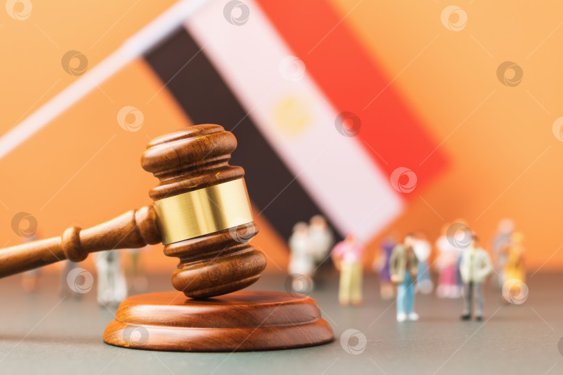 Скачать Деревянный судейский молоток, флаг и пластиковые игрушки на цветном фоне, концепция судебных процессов в египетском обществе фотосток Ozero
