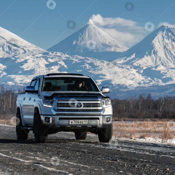 Скачать Японский спортивный внедорожник Toyota Tundra едет по дороге на фоне зимнего пейзажа полуострова Камчатка - действующего Ключевского вулкана фотосток Ozero
