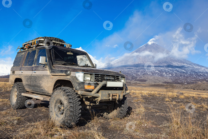 Скачать Поднятый внедорожник Toyota Land Cruiser Prado на фоне извержения действующего вулкана. Трансмиссия автомобиля модифицирована для путешествий по бездорожью фотосток Ozero