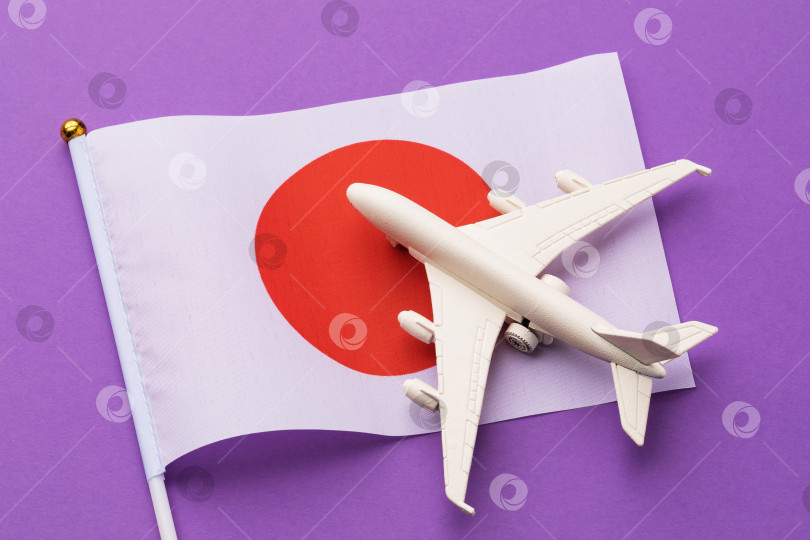 Скачать Флаг Японии и игрушечный самолет на фиолетовом фоне, концепция на тему путешествия в Японию фотосток Ozero