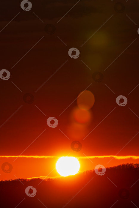 Скачать Восход солнца в горах, красный солнечный диск поднимается над вершинами горного хребта. Красивая естественная линзовая вспышка на оранжевом небе фотосток Ozero