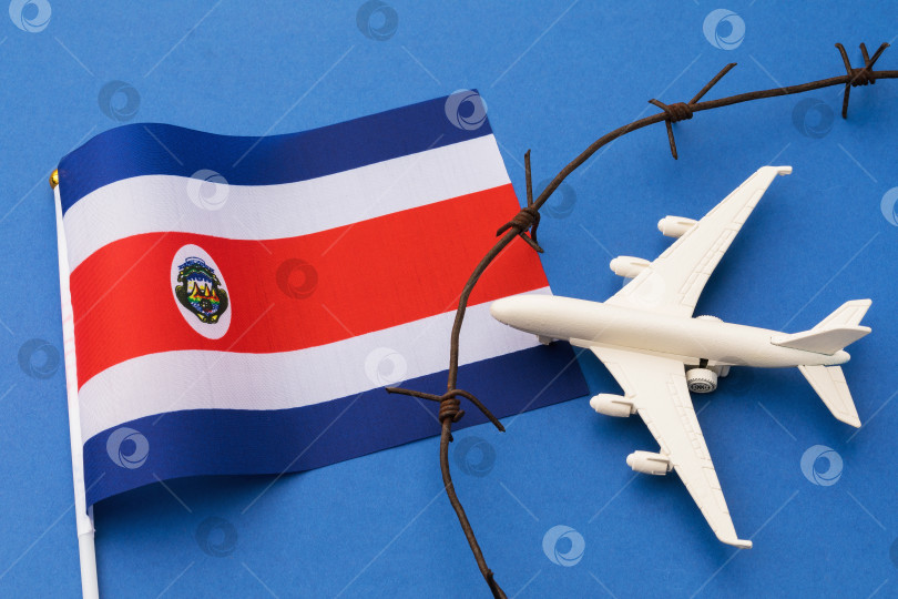 Скачать Игрушечный самолет, флаг и колючая проволока на цветном фоне, концепция нарушения воздушной границы Коста-Рики фотосток Ozero
