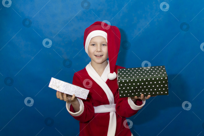 Скачать Мальчик в костюме Санты держит подарки в вытянутых руках. фотосток Ozero