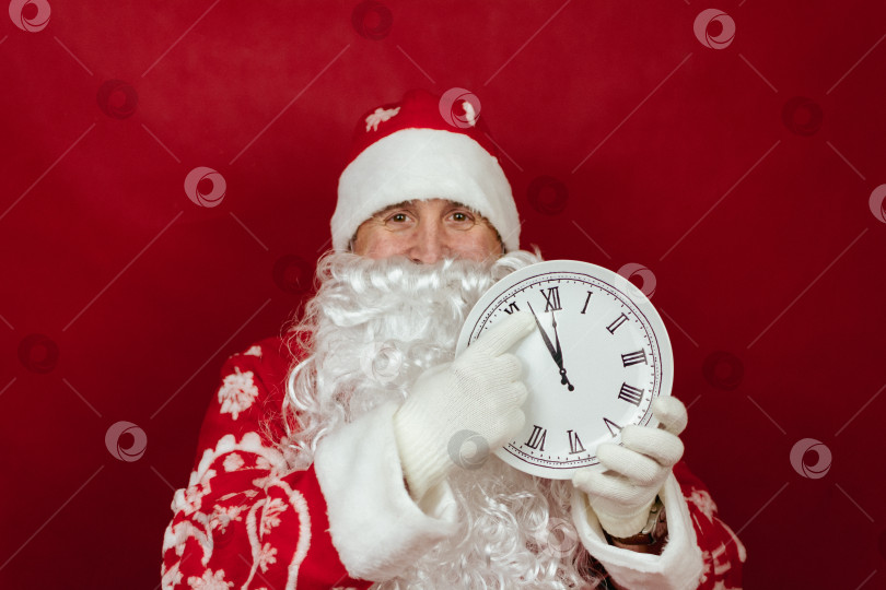 Скачать Санта держит в руках белые часы, которые показывают, что сейчас без двух минут двенадцать. закрыть фотосток Ozero